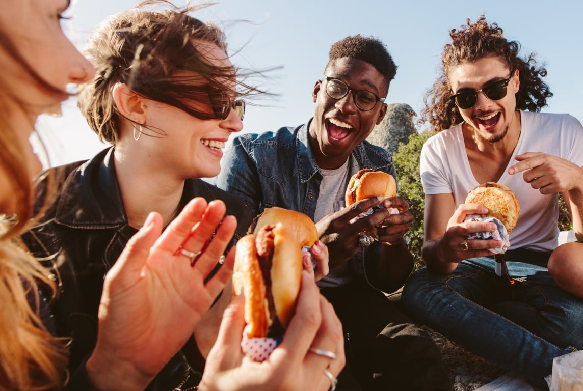 Group,Of,Friends,Sitting,On,Mountain,Top,Eating,Burger.,Excited